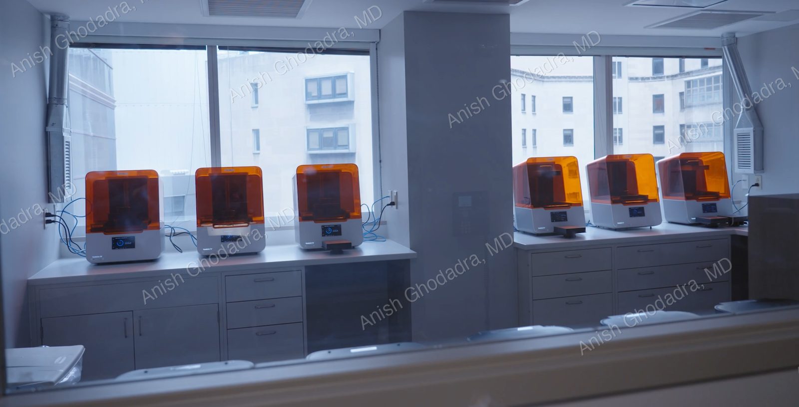 Rows of stereolithography (SLA) 3D printers seen through the window of an ISO 7 clean room at the UPMC 3D Printing Program